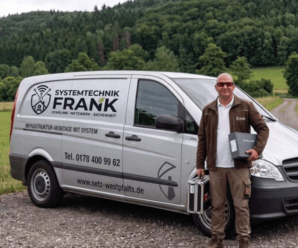 Eugen Frank vor dem beschrifteten Servicefahrzeug in der Westpfalz, mit Starlink-Hardware in der Hand